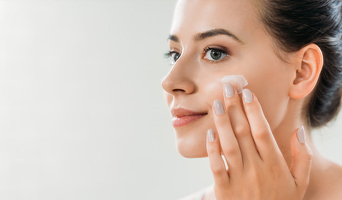 A jar of face cream, a bottle of moisturizer, and other skincare products for a daily skincare routine